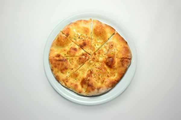 Golden hot focaccia bread topped with herbs, perfect for a delicious meal.