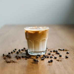 Refreshing iced latte with coffee beans on a wooden table surface.